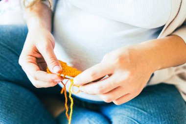 Knitting baby winter clothes. Cute pregnant woman knit fashion winter baby girl clothes. Pregnancy mother crochet kid cloth. Warm winter cozy clothes for baby