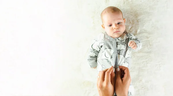 Baby cute child banner. Happy cute baby kid girl lying on white bed background. Light background. Little child. Serious emotion