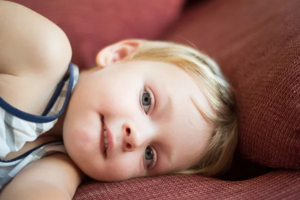 Portrait of young boy lying on sofa at home — Stock Photo, Image