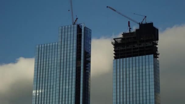 Vista time lapse di grattacieli in costruzione con gru a torre. Cielo blu con nuvole sullo sfondo. — Video Stock