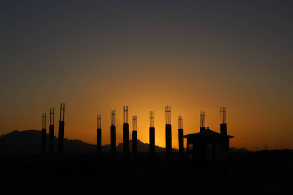 Black silhouette of unfinished building constructions on a sunset background