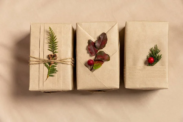 三个圣诞礼品盒 环保包装风格 亚麻布背景上有时髦褶皱和天然枝条的牛皮纸 — 图库照片