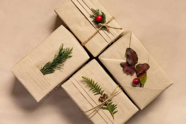 四个圣诞礼品盒 时尚和服风格与环保材料 亚麻纺织品背景上有褶皱 天然枝条和浆果的牛皮纸 — 图库照片