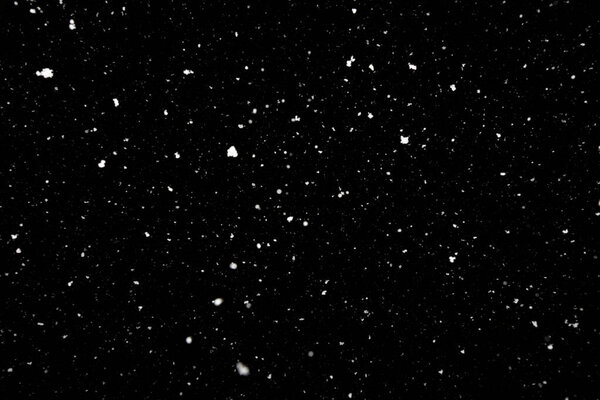 Falling snow freeze motion in the dark sky. Texture isolated on black background. Perfect for white snowflakes overlay, winter mood