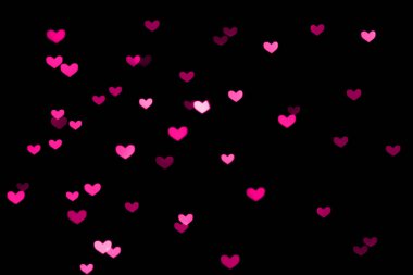 Siyah arka planda pembe, mor kalp şeklinde bokeh ışıkları.