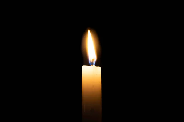 Yellow candle is burning on isolated black background. A symbol of sorrow, mourning, loss, rest in peace