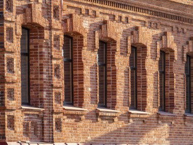 Geniş pencereli eski bir 19. yüzyıl binasının tuğla duvarı. Eski kırmızı tuğlalı bir binada altı büyük pencere..