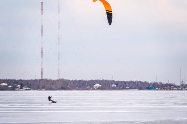 Snowboard 'da uçurtma sörfçüsü. Donmuş gölde karda kar yağıyor. Kışın kaykay