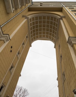 Çok katlı eski bir binada yüksek kemerli bir kapı. Moskova 'nın merkezindeki çok katlı sarı bina..