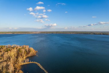 Mavi gölün kıyısında ağaçlarla dolu renkli bir sonbahar ormanı. Üst hava manzaralı. Parlak sonbahar manzarası, kuş bakışı manzaralı. Boşluk şablonunu kopyala.