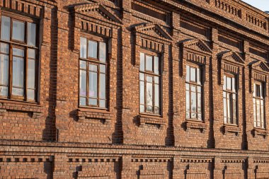 Geniş pencereli eski bir 19. yüzyıl binasının tuğla duvarı. Eski kırmızı tuğlalı bir binada altı büyük pencere..