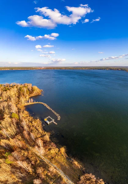 Mavi gölün kıyısında ağaçlarla dolu renkli bir sonbahar ormanı. Üst hava manzaralı. Parlak sonbahar manzarası, kuş bakışı manzaralı. Boşluk şablonunu kopyala.