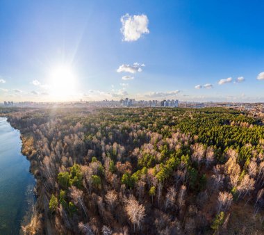 Gün batımında göl kıyısında sonbahar ormanı ve ufukta şehir, mercan manzarası. Shartash Gölü ve Yekaterinburg, Rusya