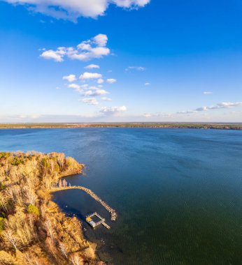 Mavi gölün kıyısında ağaçlarla dolu renkli bir sonbahar ormanı. Üst hava manzaralı. Parlak sonbahar manzarası, kuş bakışı manzaralı. Boşluk şablonunu kopyala.