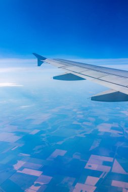 Güzel, açık mavi bir gökyüzü ve uçak kanadının penceresinden manzarayı izleyin. Dünya ve gökyüzü bir uçağın penceresinden görüldüğü gibi.