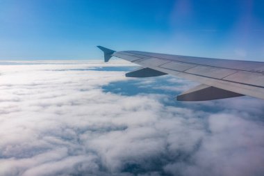 Uçak penceresinden güzel bulutlu bir gökyüzüne ve uçak kanadına bakın. Dünya ve gökyüzü bir uçağın penceresinden görüldüğü gibi.