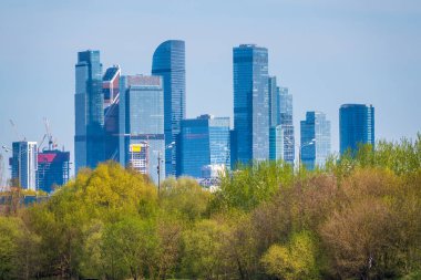 Arka plandaki yeşil ağaçlar Moskova şehrindeki modern gökdelenler. Baharda Moskova 'daki yeni binaların manzarası