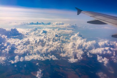 Uçak penceresinden güzel bulutlu bir gökyüzüne ve uçak kanadına bakın. Dünya ve gökyüzü bir uçağın penceresinden görüldüğü gibi.