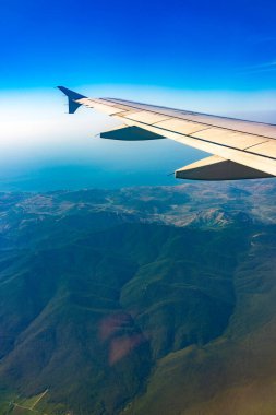 Güzel, açık mavi bir gökyüzü ve uçak kanadının penceresinden manzarayı izleyin. Dünya ve gökyüzü bir uçağın penceresinden görüldüğü gibi.