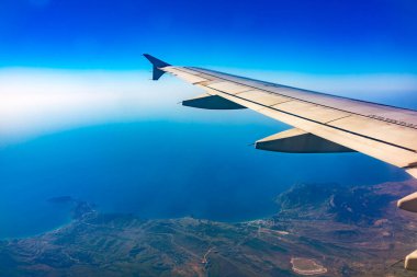 Güzel, açık mavi bir gökyüzü ve uçak kanadının penceresinden manzarayı izleyin. Dünya ve gökyüzü bir uçağın penceresinden görüldüğü gibi.