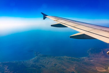 Güzel, açık mavi bir gökyüzü ve uçak kanadının penceresinden manzarayı izleyin. Dünya ve gökyüzü bir uçağın penceresinden görüldüğü gibi.