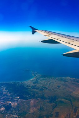 Güzel mavi gökyüzü, toprak, deniz ve uçak kanadına uçak penceresinden bakın. Dünya, deniz ve gökyüzü bir uçağın penceresinden görüldüğü gibi.