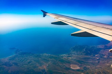 Güzel mavi gökyüzü, toprak, deniz ve uçak kanadına uçak penceresinden bakın. Dünya, deniz ve gökyüzü bir uçağın penceresinden görüldüğü gibi.