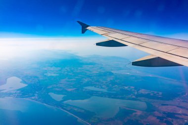 Güzel mavi gökyüzü, toprak, deniz ve uçak kanadına uçak penceresinden bakın. Dünya, deniz ve gökyüzü bir uçağın penceresinden görüldüğü gibi.