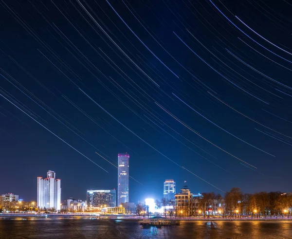 市内中心部の池のほとりに早春の夜 星の軌道を持つ星空 照明付きの建物 Yekaterinburg Russia — ストック写真