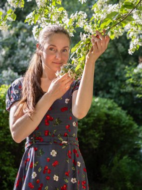 Bahar parkında çiçek açan ağaçların arasında makyajsız güzel bir genç kadın. Doğal makyajsız, başını yeşil arka plana eğmiş bir kızın yakın plan portresi. Bahar geliyor..