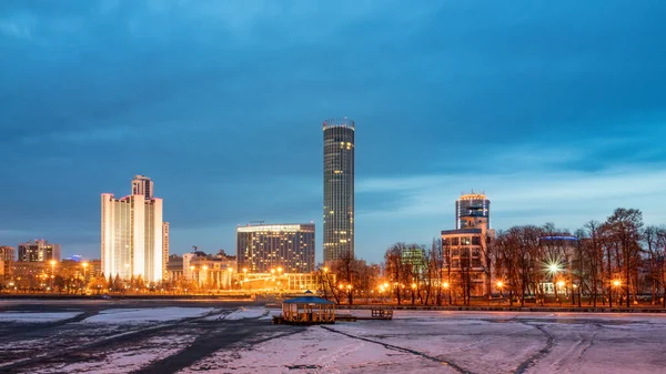 Şehir merkezindeki göletin kıyısında bahar gecesi erken saatlerde. Aydınlatılmış binalar. Bahar geldi. Nehirdeki buz erimeye başladı. Yekaterinburg, Rusya