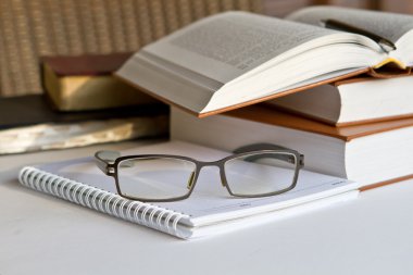 Not defteri ve gözlük ile kitap yığını