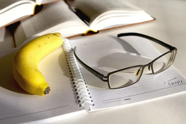 Banana e óculos em um bloco de notas — Fotografia de Stock