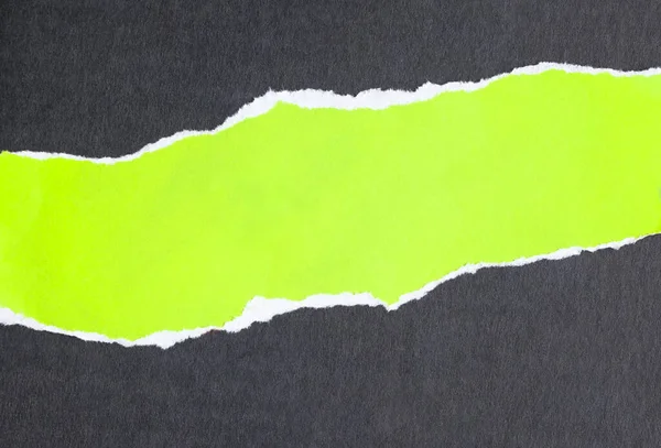 Ripped fluorescent green paper on black background. Copy for advertising space.