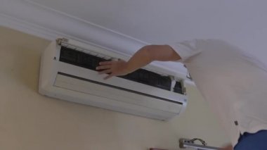 Adam tozlu klima filtrelerini kaldırıyor. Ev temizliği ve bakım konsepti.