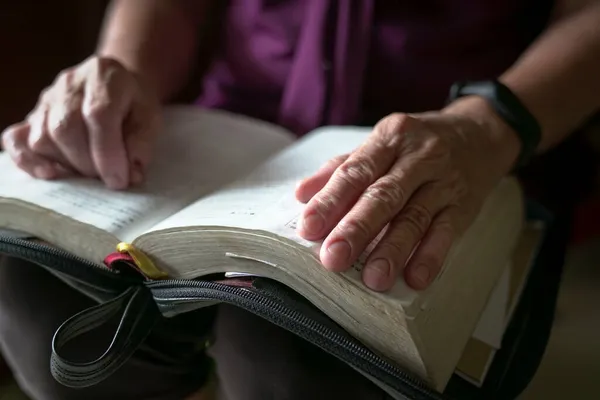 老妇人皱着眉头摸着一本打开的书 — 图库照片