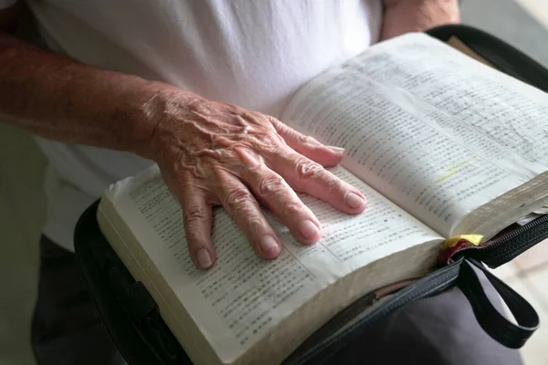 老人在一本打开的圣经上面擦伤的手 — 图库照片