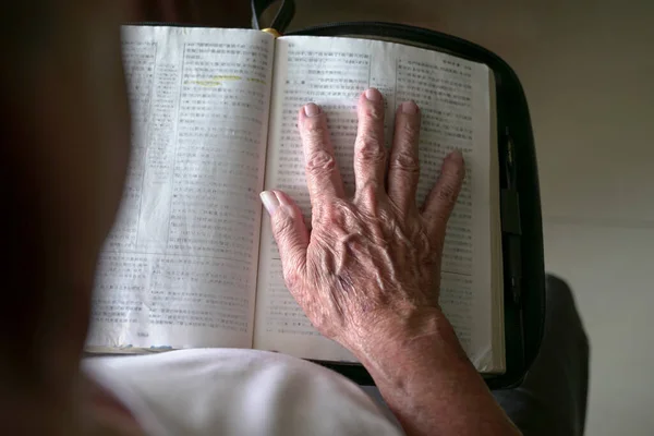 老人的手放在一本打开的中国圣经之上 — 图库照片