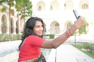 Asyalı Hintli kadın akıllı telefon kullanarak kendi portresini ya da görüntülü sohbetini çekiyor.