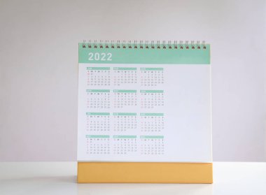 2022 takvim yılı bir sayfada. Masa takvimi, kopyalama alanı olan beyaz masanın üzerinde oturur.