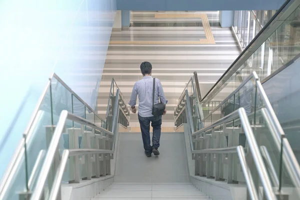 Man going down the stairs of a modern building. Going home from work or urban living concept.
