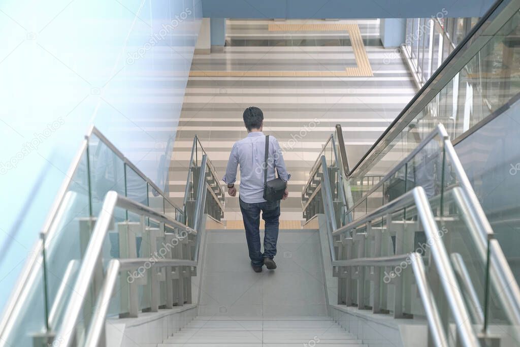 Man going down the stairs of a modern building. Going home from work or urban living concept.