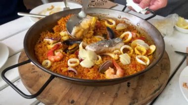 Lezzetli deniz ürünleri paella, ünlü İspanyol paella tavası midye, midye, balık, mürekkep balığı ve karidesli lezzetli pirinç yemeğinden oluşur.