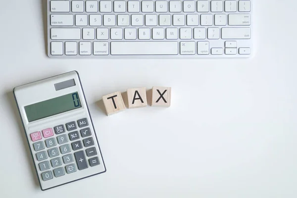 計算機とキーボードの横にある木製の立方体の上に税金という言葉 税務申告の概念 — ストック写真
