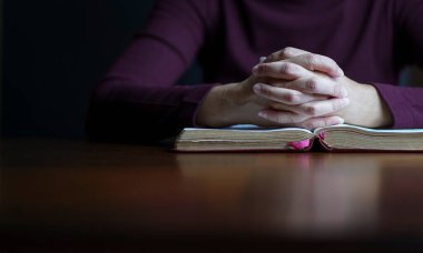 Kadın elleri dua pozisyonunda açık incilin üstünde. Boşluğu kopyala.