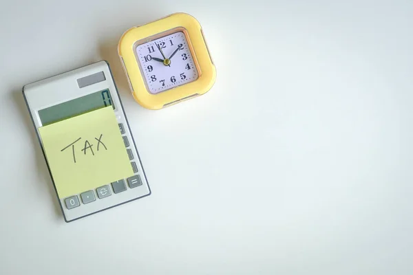 黄色の接着剤紙の単語税 黄色の時計の横に計算機に固執する 最上階だ 税務申告の概念 — ストック写真