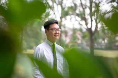 İyi giyimli Asyalı iş adamı gülümsemesi. Konut geçmişi olan doğa..