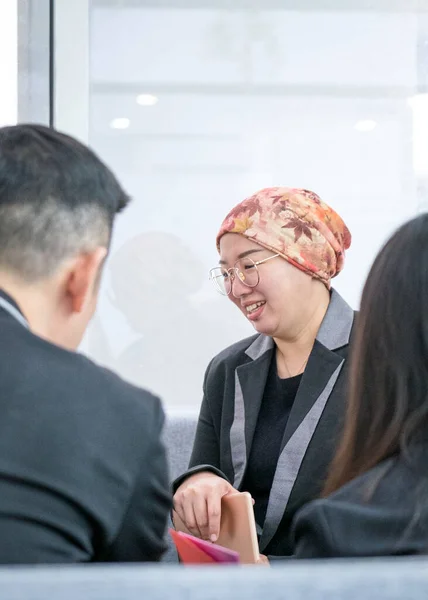 Asian businesswoman smiling while talking to customers. Modern office setting.