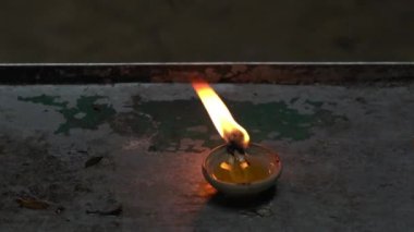 Close up view of a diva oil lamp candle burning and glowing on a table in temple.