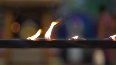 Close up view of diya oil lamps candle burning and glowing in temple. Blur devotees in the background.